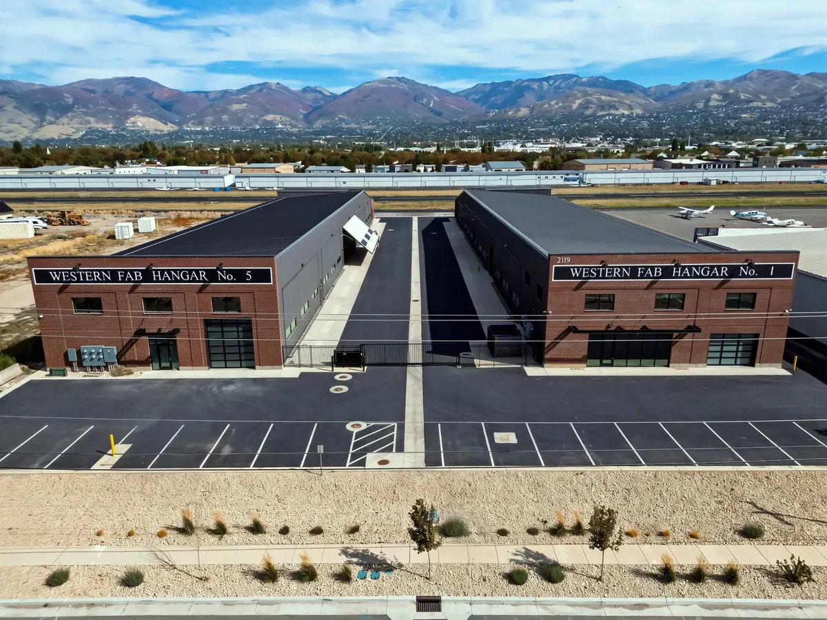 Aerial front view of two Western Fab airplane hangar buildings with brick facades and mountain backdrop