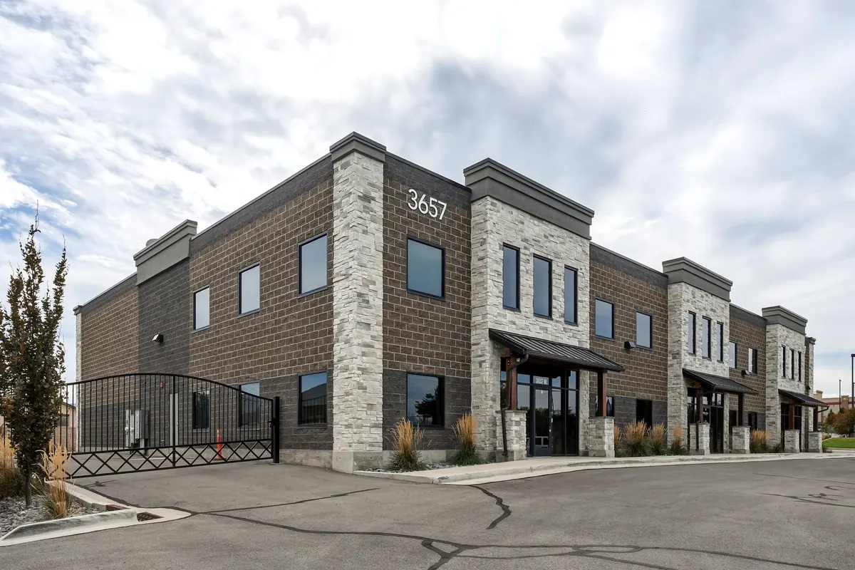 Three-quarter view of a two-story brick commercial building with storefront entrance and parking
