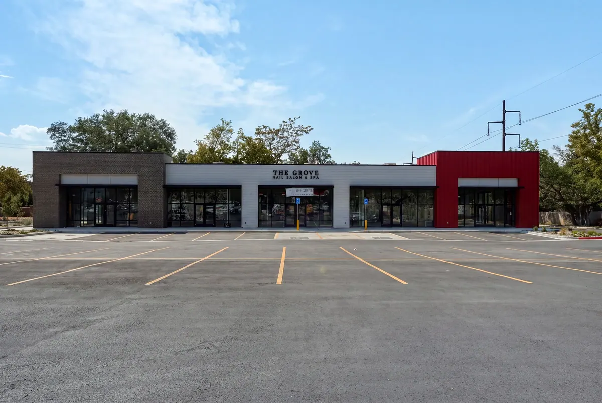 Front elevation of the 8th and 9th retail building with dark brick and red metal accents