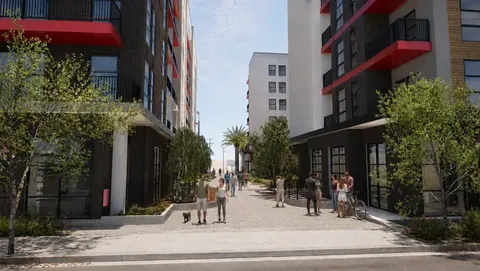 Pedestrian street between modern multifamily buildings with red accent balconies and landscaped walkway