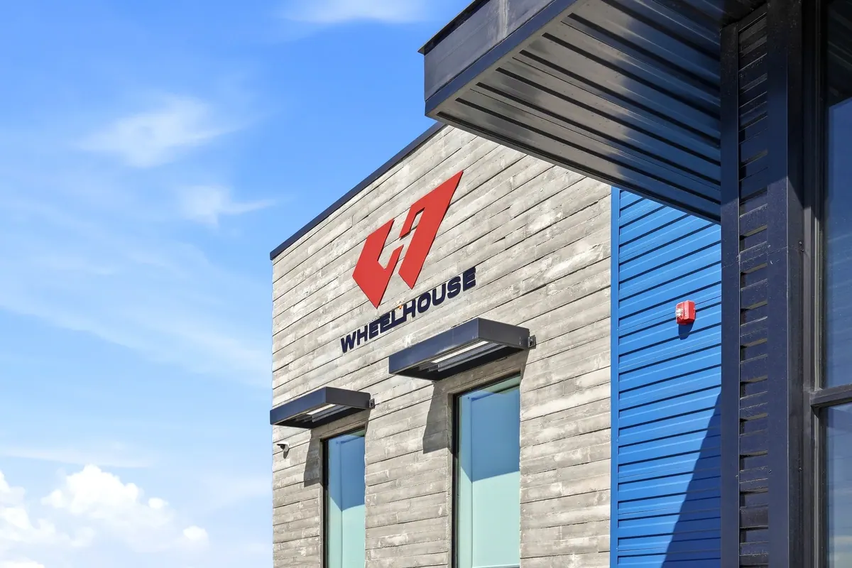 Close-up of the Wheelhouse racing facility sign and blue metal-clad exterior