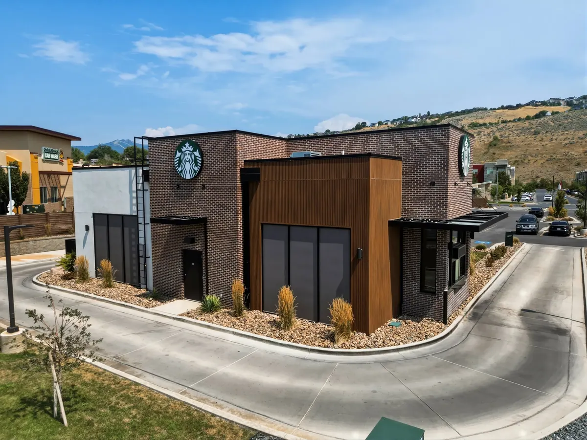 Elevated view of Starbucks building with brick and wood-look facades beside the drive-through lane.