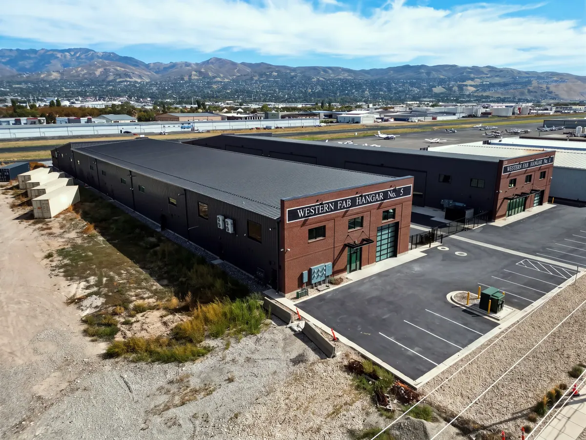 Oblique aerial view of the Western Fab airplane hangars with parking, adjacent buildings and mountains