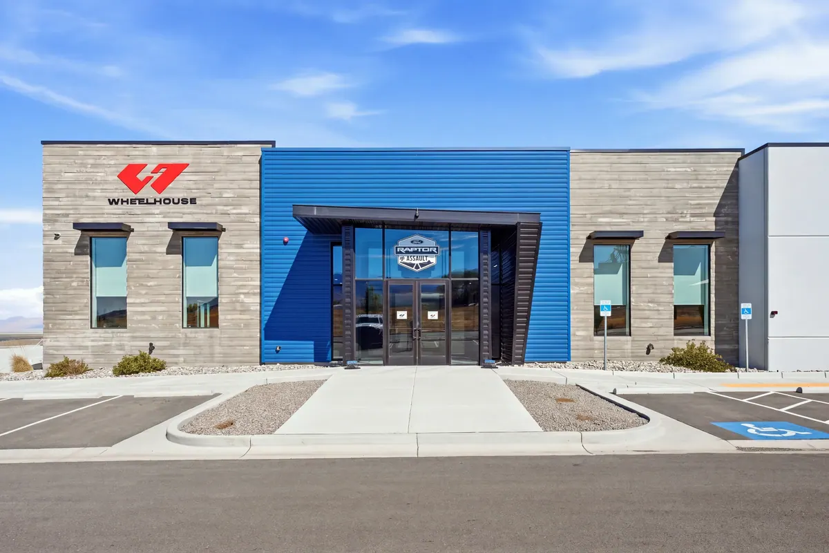 Front entrance to the Wheelhouse racing facility with blue accent facade and accessible parking