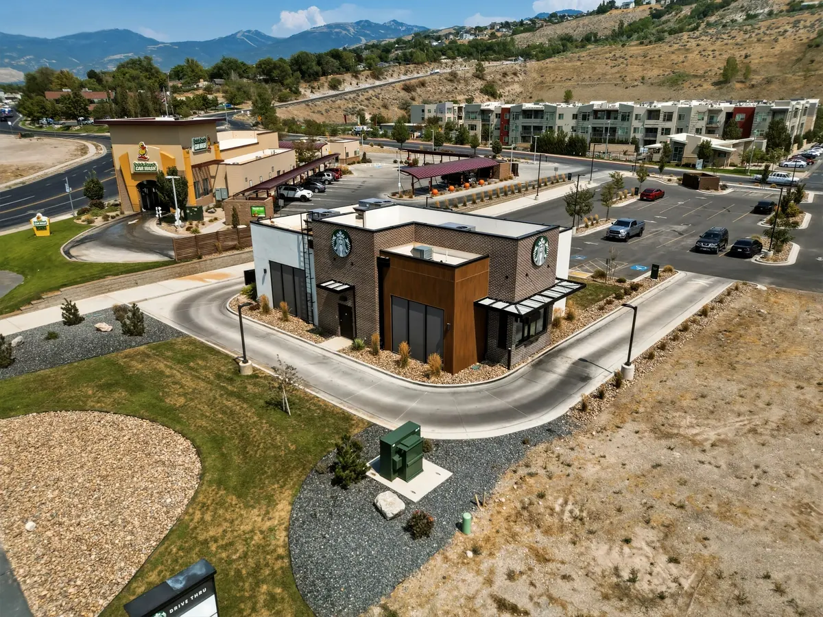 Aerial view of the standalone Starbucks building, adjacent retail development, access drives and surrounding landscape.