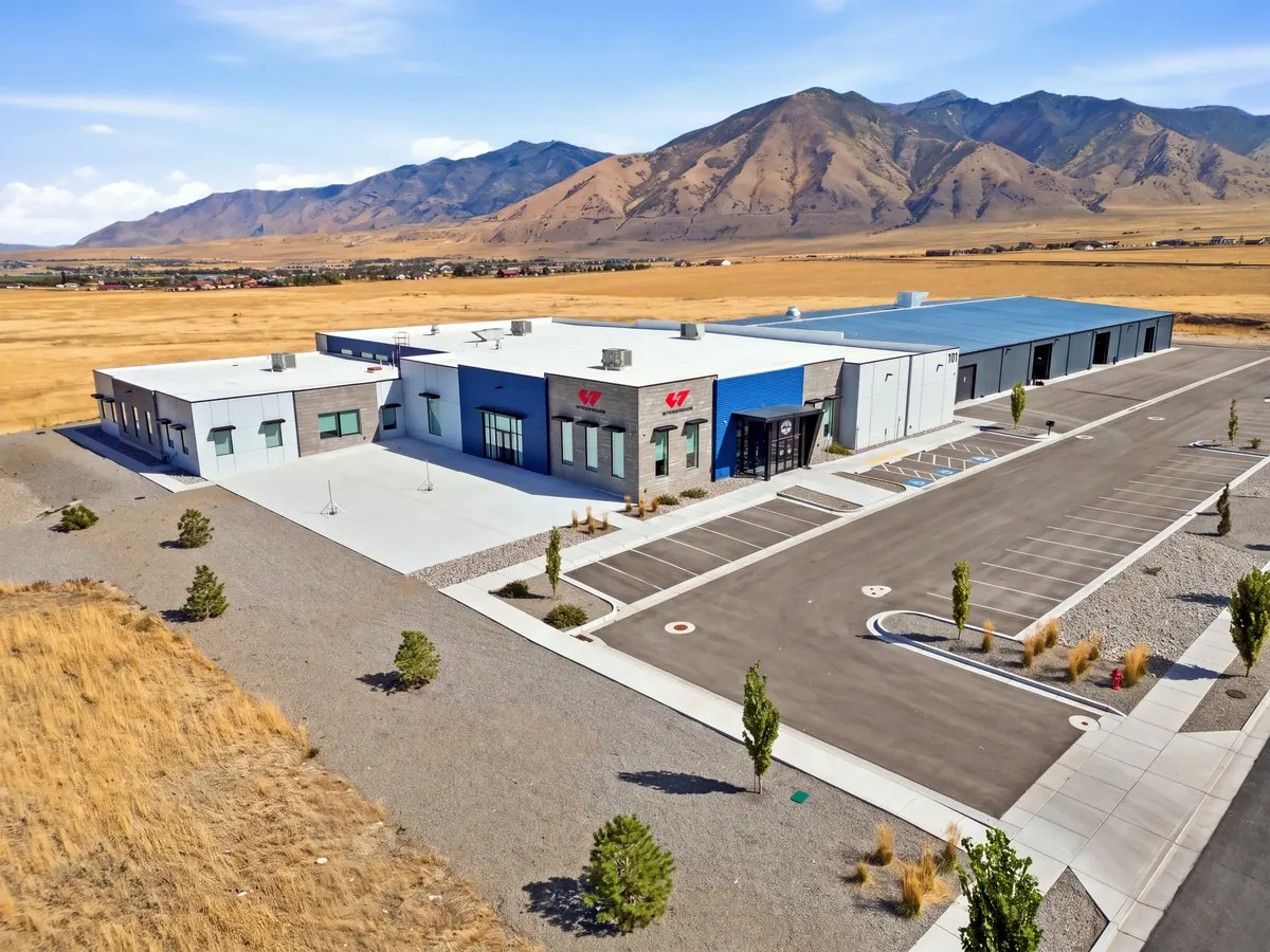 Aerial view of the Wheelhouse racing facility with training building, paved site and mountain backdrop