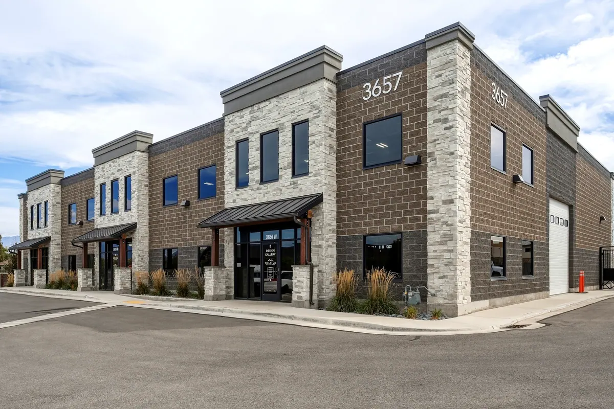 Street-level corner view of a two-story brick commercial building and landscaped frontage
