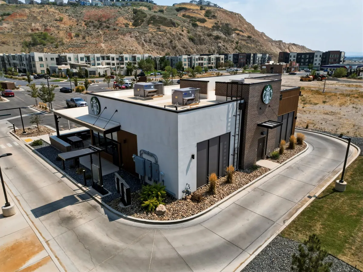 Elevated rear view of the Starbucks building showing rooftop equipment, drive-through circulation and neighboring buildings.